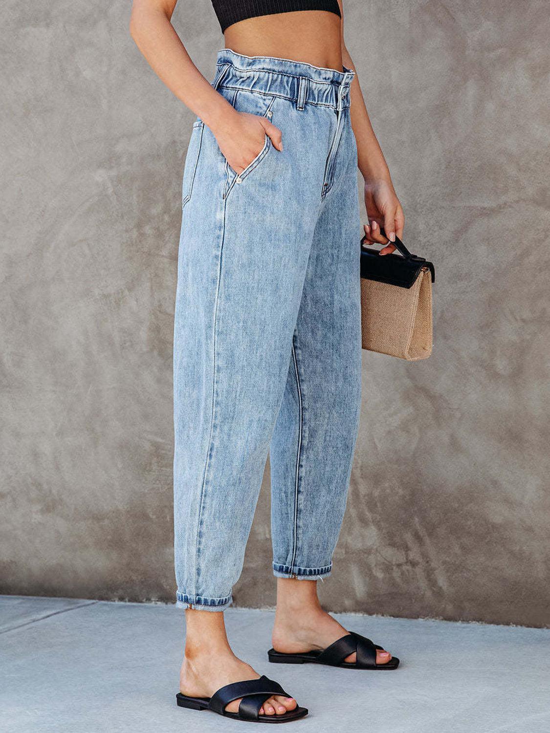 a woman in a crop top and jeans holding a purse