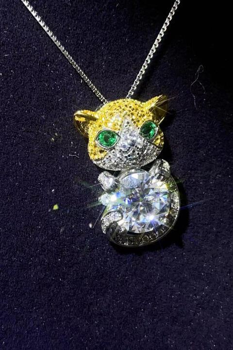 a necklace with a cat on it on a black surface