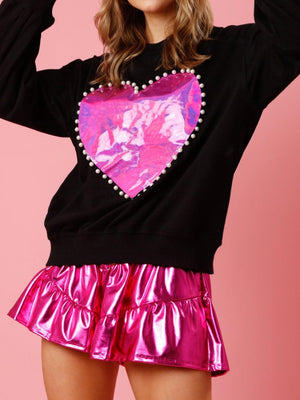 a woman wearing a pink skirt and a black sweatshirt