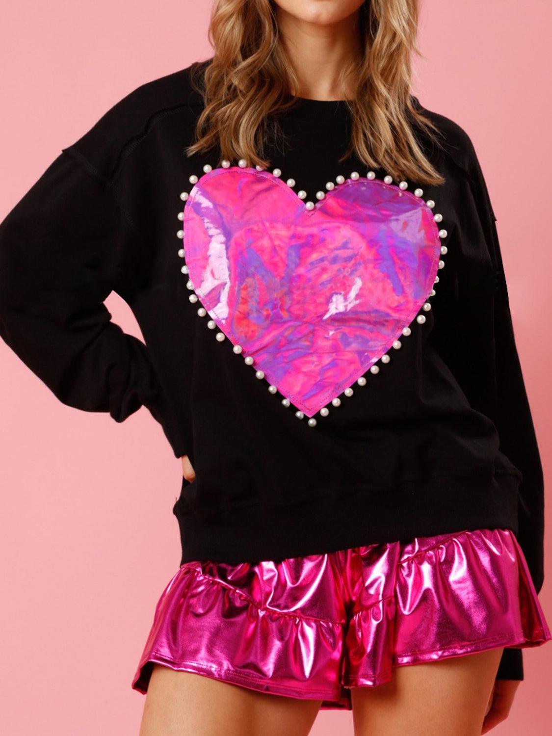 a woman wearing a black sweatshirt with a pink heart on it