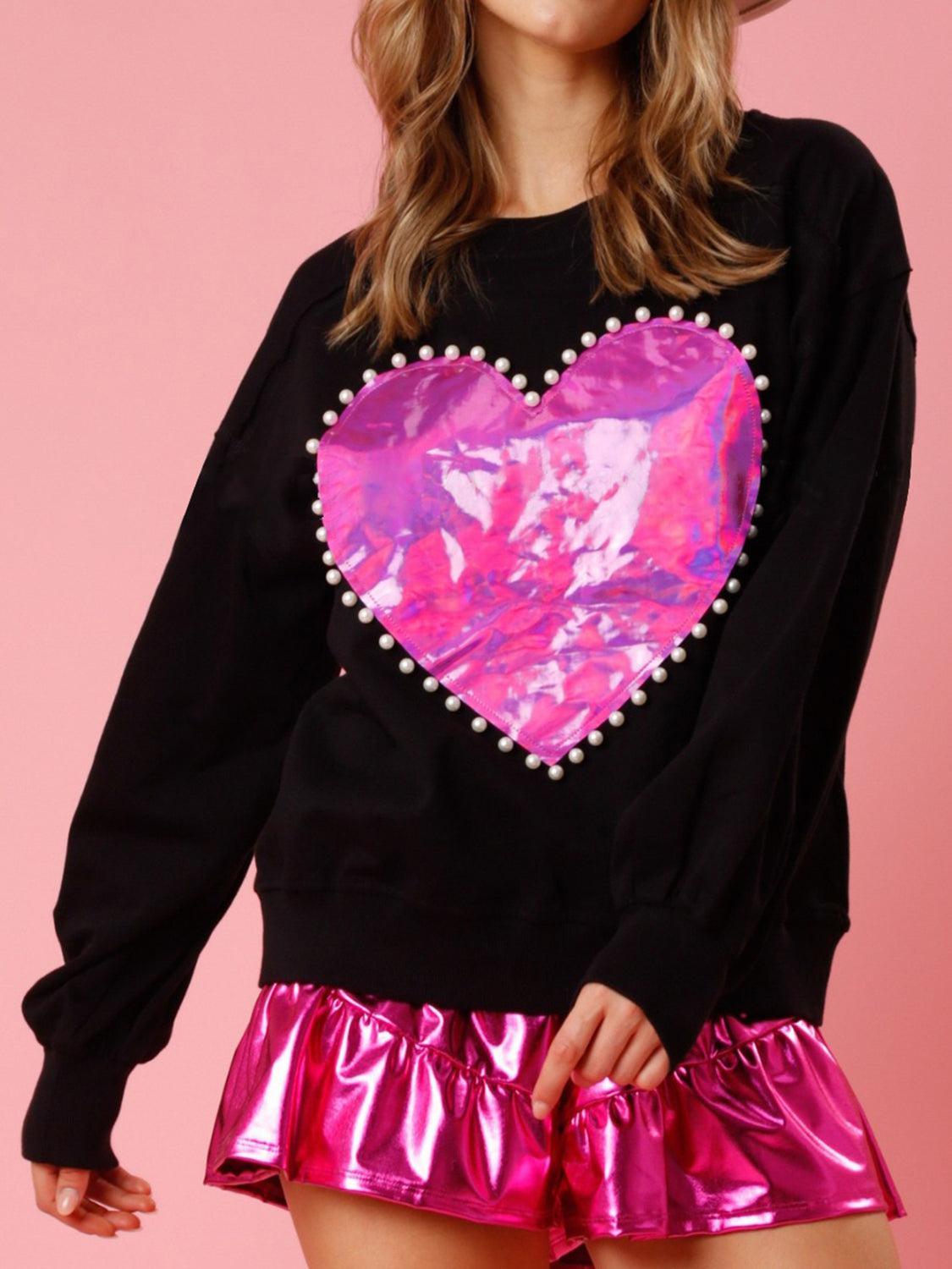 a woman wearing a black sweater with a pink heart on it