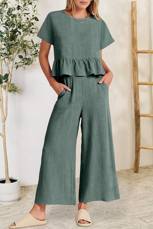 a woman wearing a green top and wide legged pants