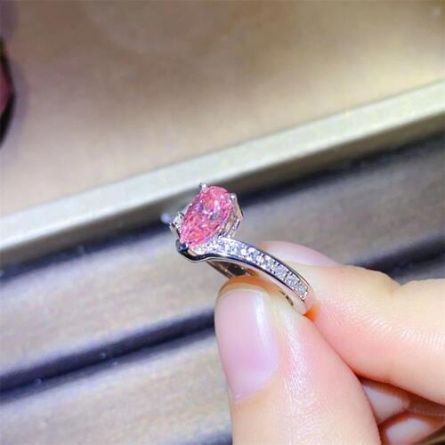 a woman's hand holding a pink diamond ring