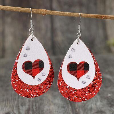 a pair of red and white earrings hanging from a wooden stick