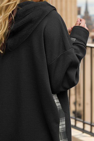 a woman in a black hoodie is standing on a balcony