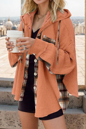 a woman in an orange jacket holding a cup of coffee