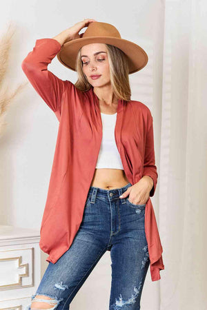 a woman wearing a red cardigan and ripped jeans