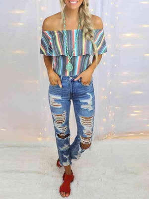 a woman wearing ripped jeans and a striped top