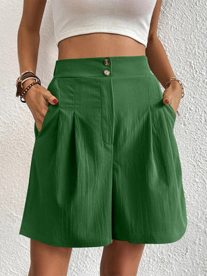 a woman wearing a white top and green shorts