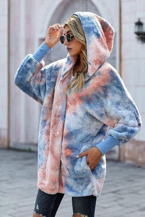 a woman wearing a tie dye hoodie and ripped jeans