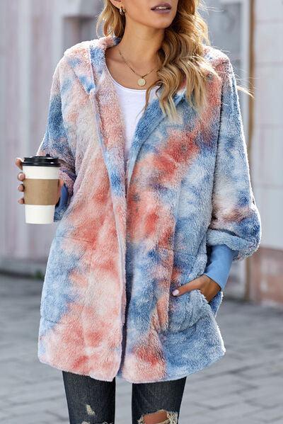 a woman in a tie dye coat holding a cup of coffee