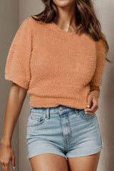 a woman wearing a short denim shorts and a fuzzy sweater