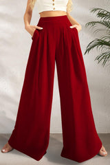 a woman in a white crop top and red wide legged pants