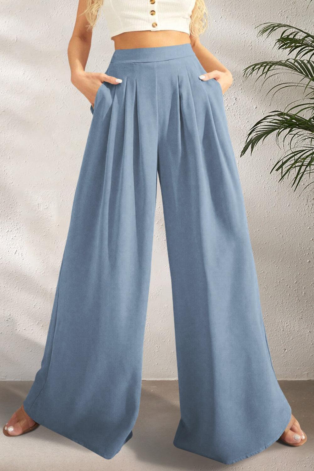 a woman in a white crop top and blue wide legged pants