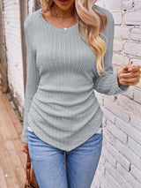 a woman wearing a gray sweater and jeans