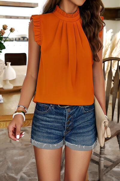 a woman in an orange top and denim shorts