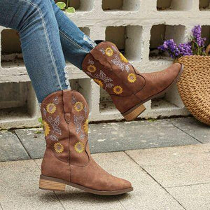 a woman wearing brown cowboy boots with sunflowers on them