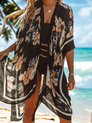 a woman standing on a beach wearing a black and white floral kimono