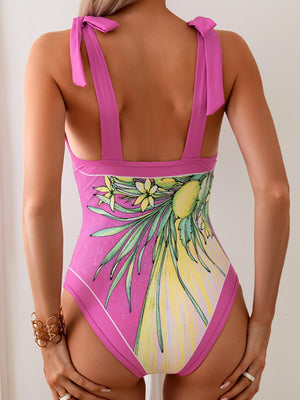 a woman in a pink one piece swimsuit with flowers on it