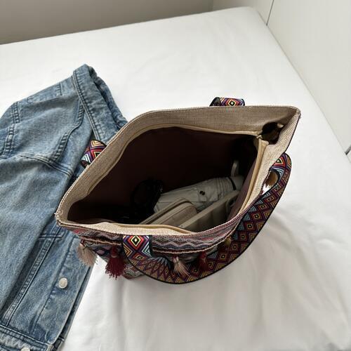 a purse sitting on top of a bed next to a pair of jeans