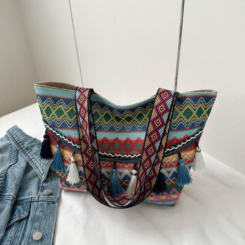 a handbag and a pair of jeans on a bed