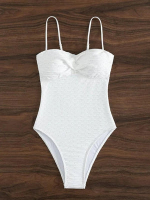 a white one piece swimsuit on a wooden surface