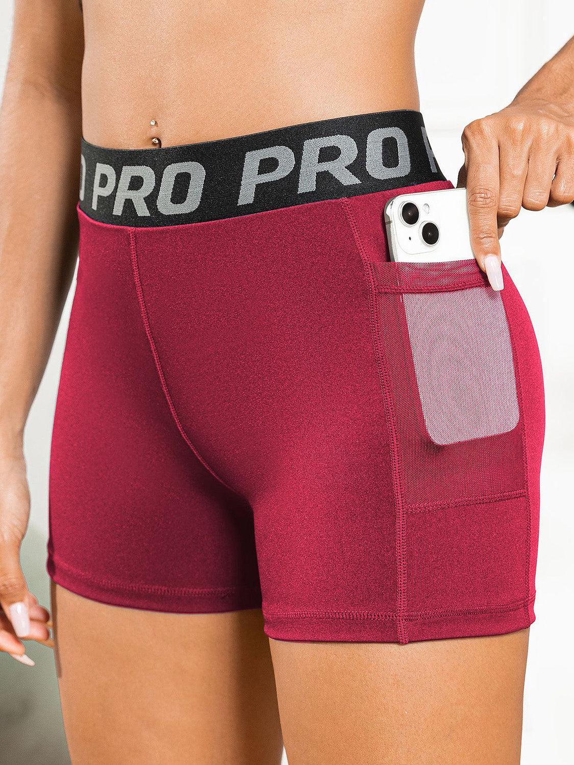 a woman in red shorts holding a cell phone in her pocket