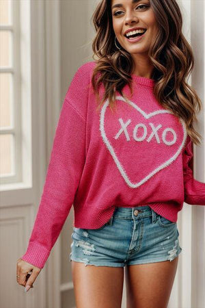 a woman wearing a pink sweater with a heart on it