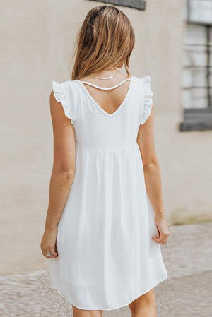 a woman in a white dress walking down a street