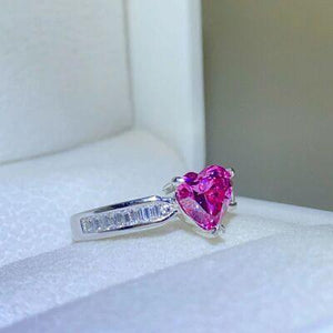 a pink heart shaped diamond ring sitting on top of a white box