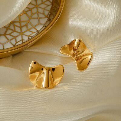 a pair of gold earrings sitting on a white cloth