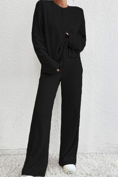 a woman wearing a black sweater and wide legged pants