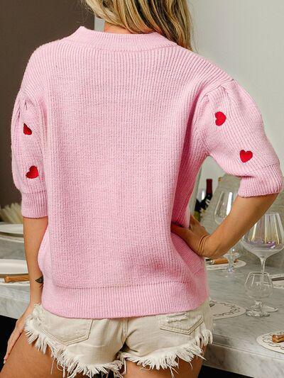 a woman wearing a pink sweater with hearts on it
