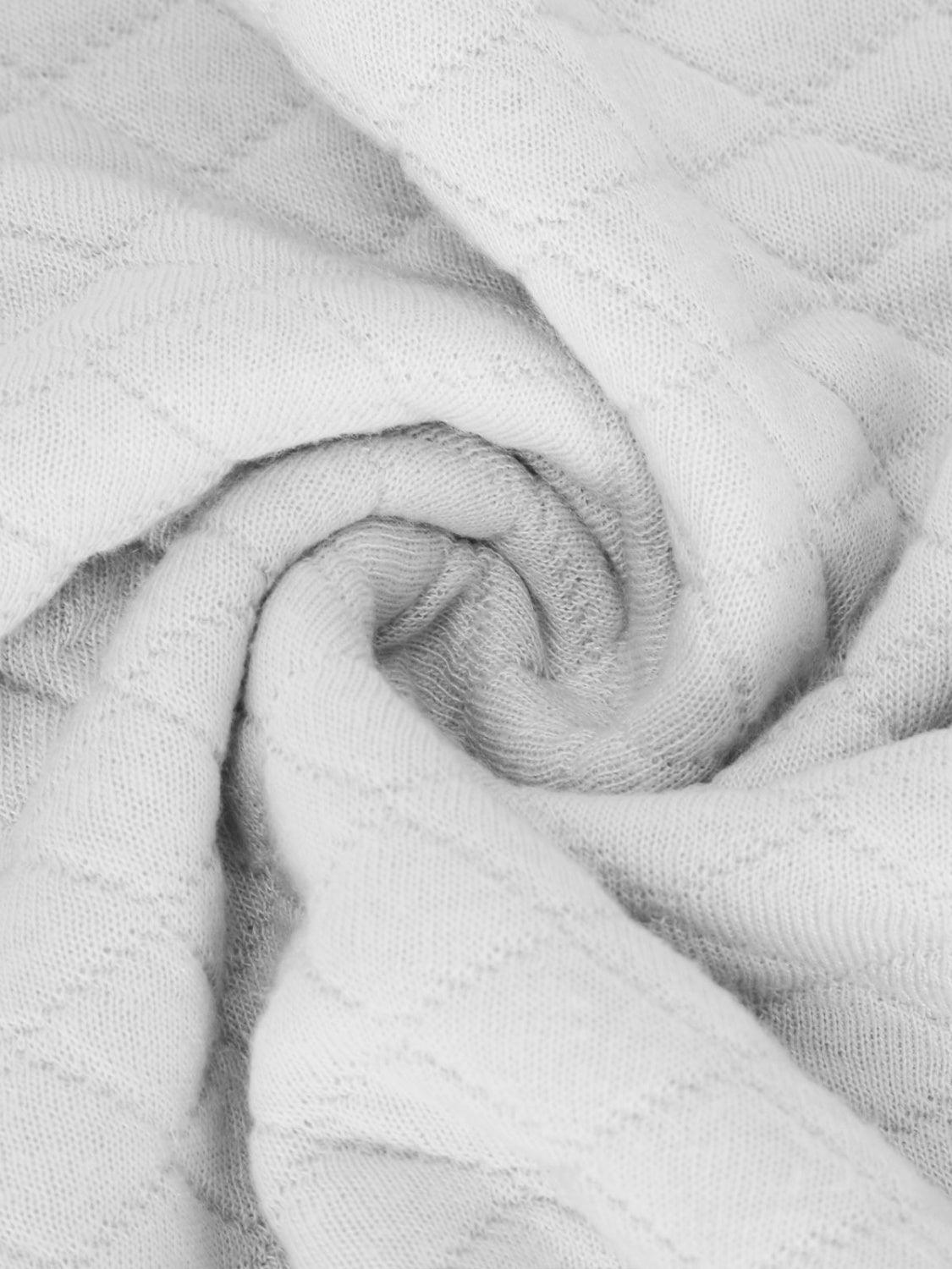a white blanket is folded up on a bed