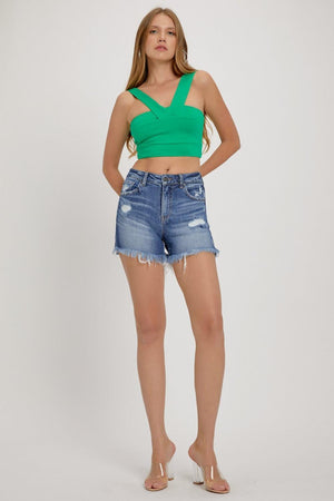 a woman wearing a green top and denim shorts