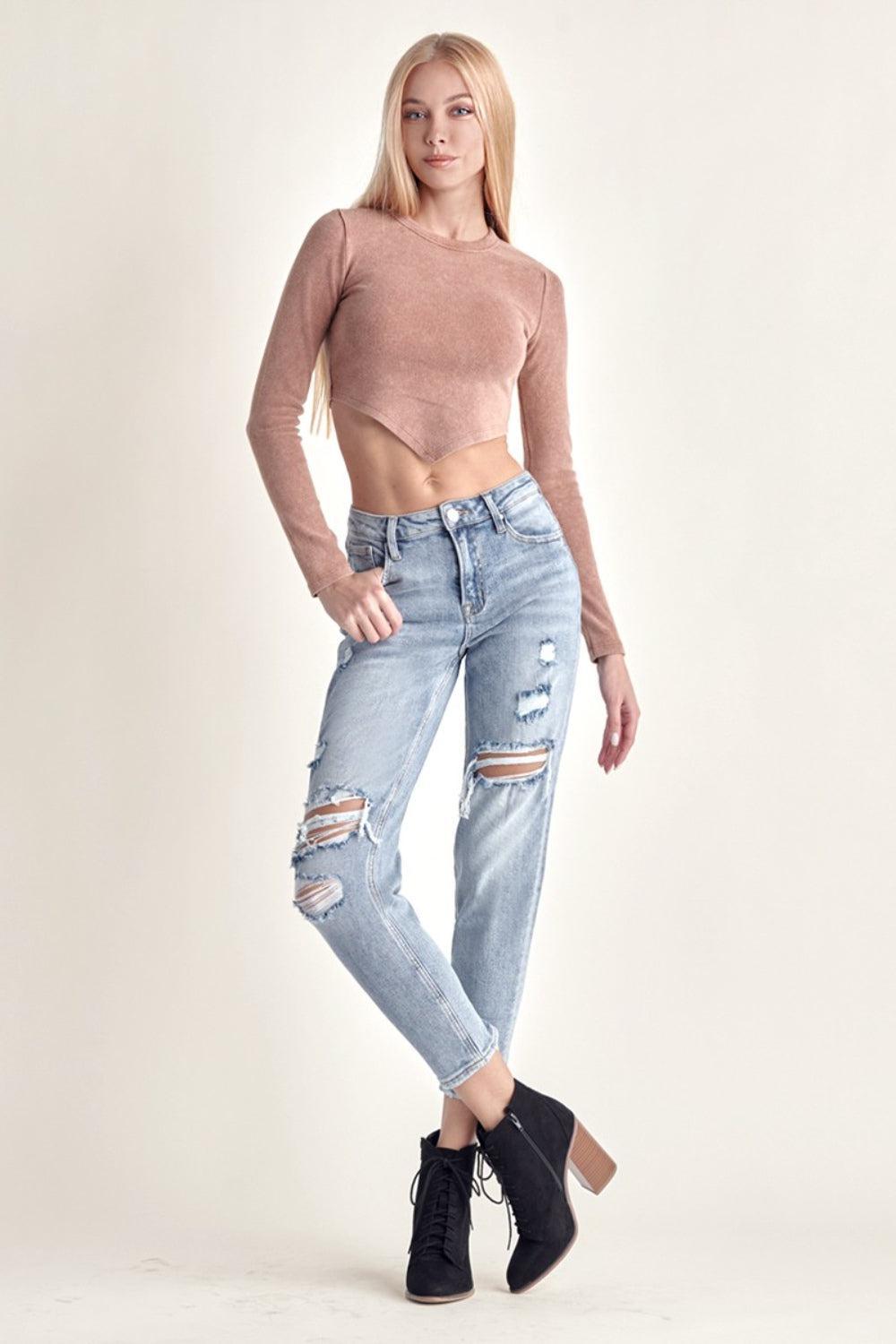 a woman wearing ripped jeans and a crop top