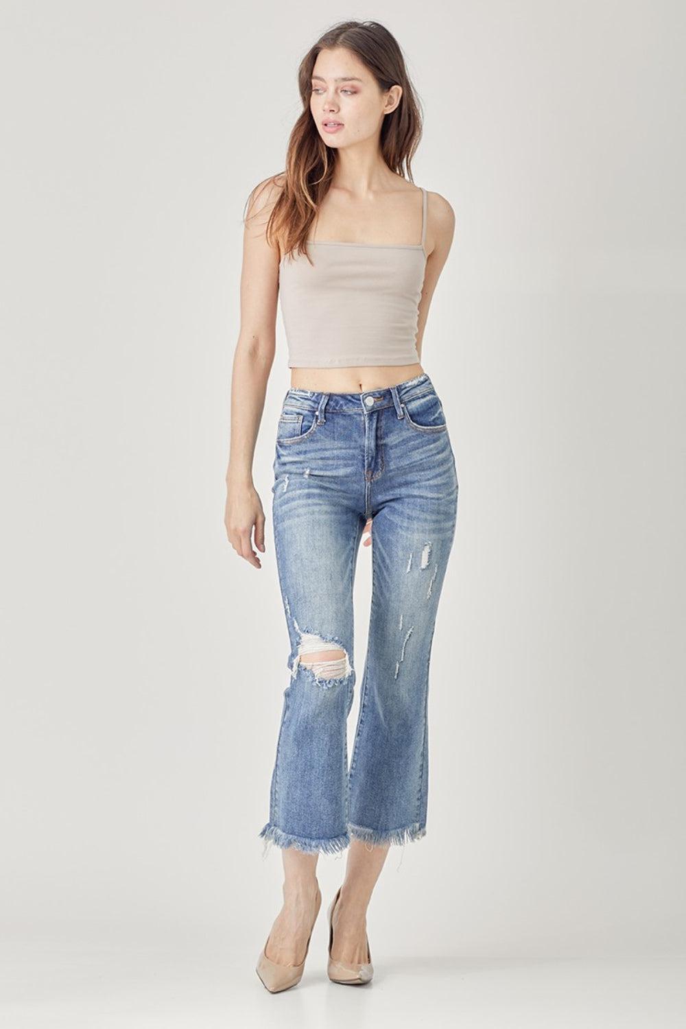 a woman in a cropped tank top and ripped jeans