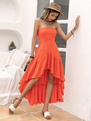 a woman in an orange dress leaning against a wall