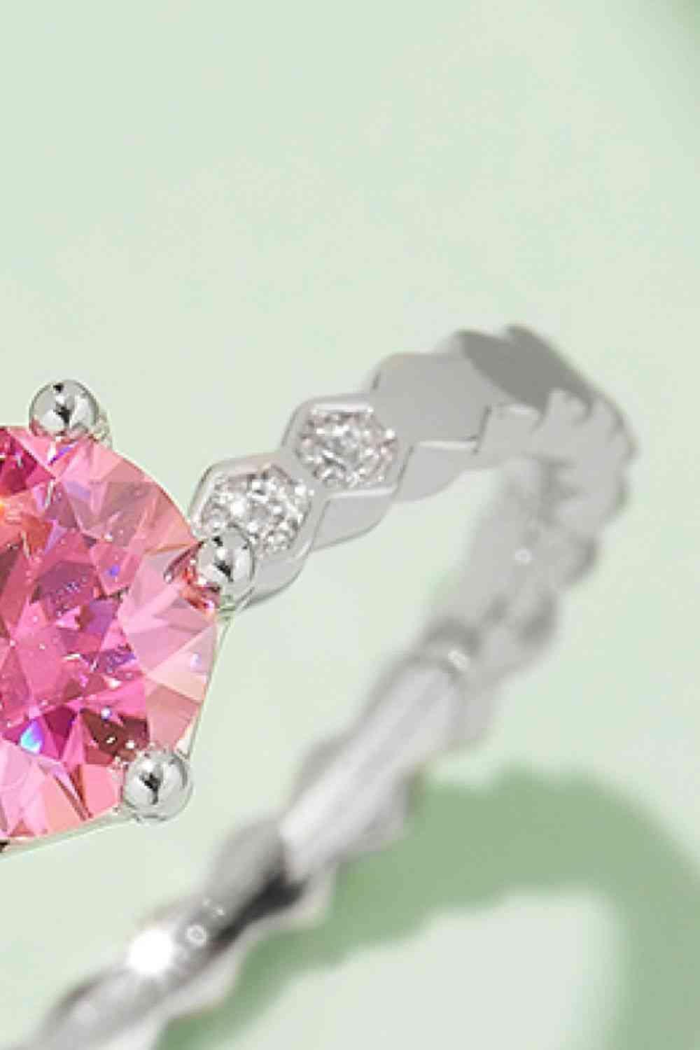 a pink diamond ring on a green background