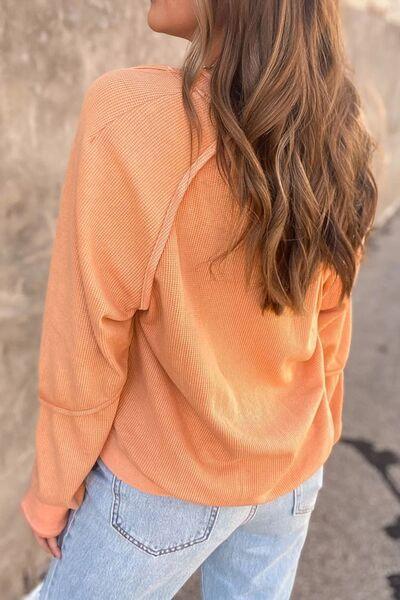 a woman wearing an orange sweater and jeans