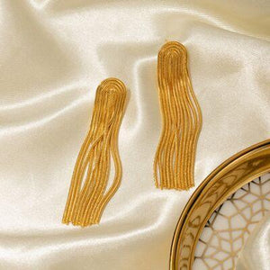 a pair of gold earrings sitting on top of a white cloth