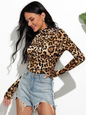 a woman wearing a leopard print top and denim shorts