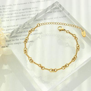 a gold bracelet on a clear box with a flower