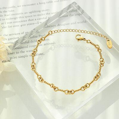 a gold bracelet on a clear box with a flower