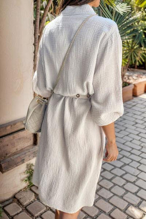 a woman in a white dress walking down a sidewalk