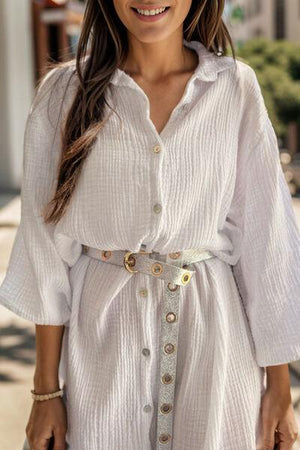 a woman wearing a white shirt dress with a belt