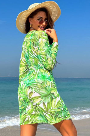 a woman in a green dress and hat on the beach