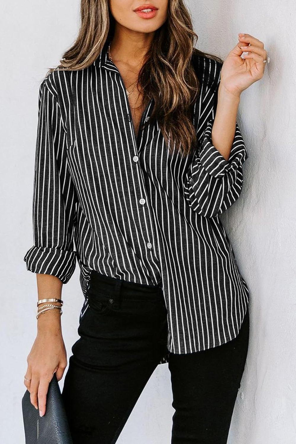 a woman leaning against a wall wearing a black and white striped shirt