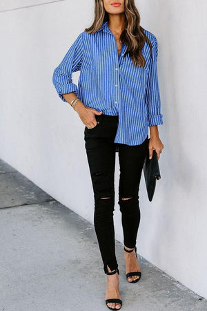 a woman wearing a blue striped shirt and black ripped jeans