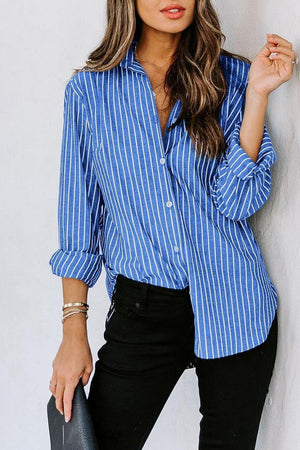 a woman leaning against a wall wearing a blue and white striped shirt